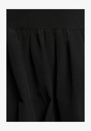 Tissu noir avec des plis froncés créant des plis verticaux texturés et des ombres douces.