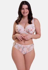 Set di reggiseno e slip in pizzo color pesca e bianco, con motivi floreali, pannelli trasparenti e un delicato dettaglio a fiocco al centro del reggiseno.