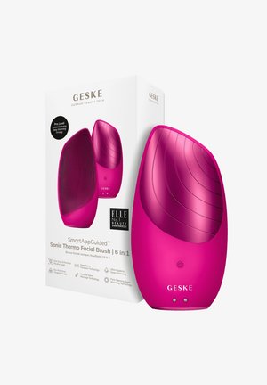 Sonic termo ansiktsborste med en elegant, böjd rosa kropp, texturerade silikonestrån och en slät ergonomisk design för enkel hantering.