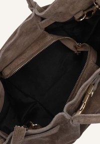 Bruine suède handtas met een zachte textuur, met een zwarte interieur en gouden hardware. Ritsafsluiting en zichtbare compartimenten.