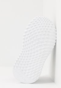 Suela de zapatilla blanca con un agarre texturizado que presenta un patrón hexagonal, fabricada en goma, mostrando el nombre de la marca "adidas" en el costado.
