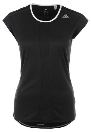 Femme portant une tenue de sport Adidas noire, comprenant un t-shirt à manches courtes, un short avec des bandes blanches, et des chaussures de sport noires avec des semelles blanches.
