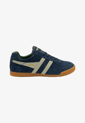 Marineblauwe suède sneaker met beige strepen, gumrubberen buitenzool en groene binnenvoering. Gouden logo op de tong voegt detail toe.