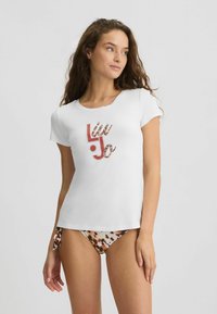 Balta marškinėliai su apvalia iškirpte ir trumpomis rankovėmis, kuriuose logotipe yra leopardų rašto akcentas. Dėvimi su raštuotais bikiniais.