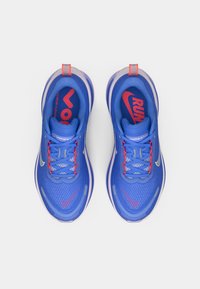 Μπλε αθλητικά παπούτσια με πλέγμα επάνω, κόκκινες λεπτομέρειες στα κορδόνια και το λογότυπο, υφασμάτινη εσωτερική σόλα και ορατή απορρόφηση κραδασμών. Διαθέτουν μια ανακλαστική λογότυπη λεπτομέρεια Swoosh.