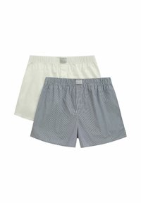 Deux paires de boxers pour hommes : une blanche unie, l'autre marine avec des rayures blanches. Les deux disposent de ceintures élastiques et d'étiquettes de marque à l'avant.