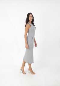 Graues geripptes Midikleid mit Schulterträgern, Frontknöpfen und einer kleinen Tasche. Tragen mit klaren Absatzsandalen. Glattes Material und taillierte Form.
