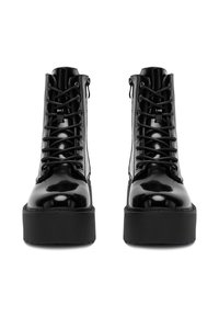 Czarne, błyszczące buty wojskowe na platformie, wyposażone w sznurówki i boczne zamki, co ułatwia zakładanie. Gładka tekstura z wzmocnionymi detalami przeszycia.