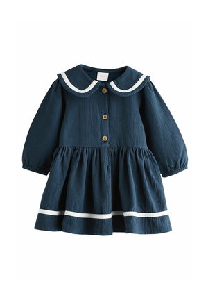 Granatowa sukienka z długimi rękawami, kołnierzykiem wykończonym białą lamówką, zapinana na guziki z marszczoną spódnicą z białymi akcentami u dołu.