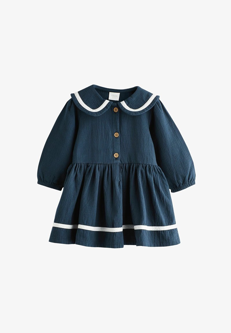 Robe bleu marine avec des manches longues, un col bordé de blanc, un devant boutonné et une jupe froncée avec des accents blancs au niveau de l'ourlet.