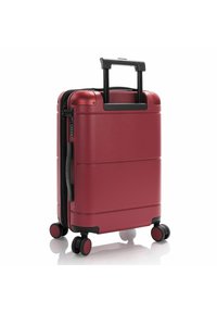 Red hard-shell carry-on suitcase with a textured surface, black handle, zipper, and four spinner wheels for easy mobility.