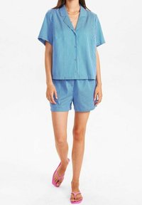 Blå och vit randig kortärmad skjorta och shorts-set; mjukt tyg; avslappnad passform; kombinerat med rosa flip-flops.