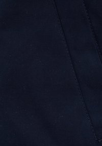 Marinblått tyg med en slät textur och subtil lyster. Har en synlig söm och lätt luddrig yta.