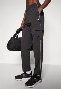 Melnas kravas bikses ar baltu svītru, elastīgu jostu un kabatām. Apvienotas ar melniem sporta apaviem ar rozā akcentiem.