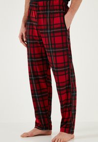 Rode schotse pyjamabroek met zwart-witte accenten, met een ontspannen pasvorm, elastische tailleband en zijzakken. Glad katoenmateriaal.