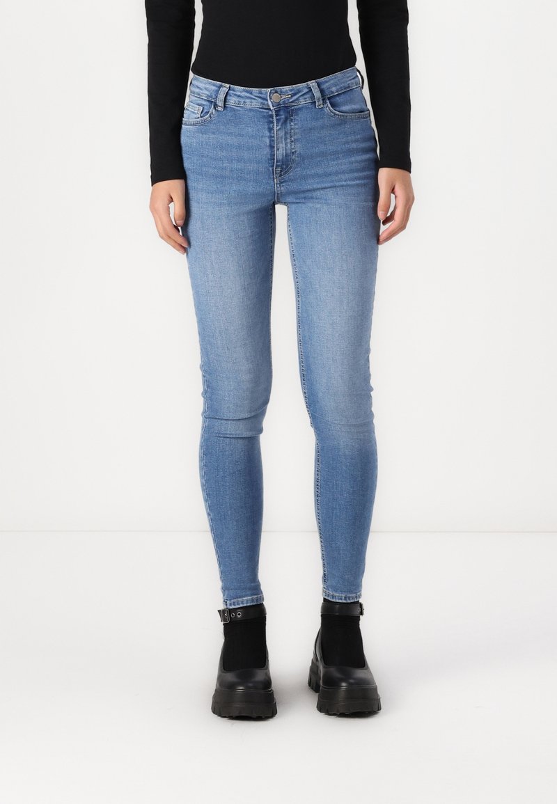 Jeans skinny azul claro de mezclilla, con una cintura de media altura, sutiles desgastes y un clásico diseño de cinco bolsillos.