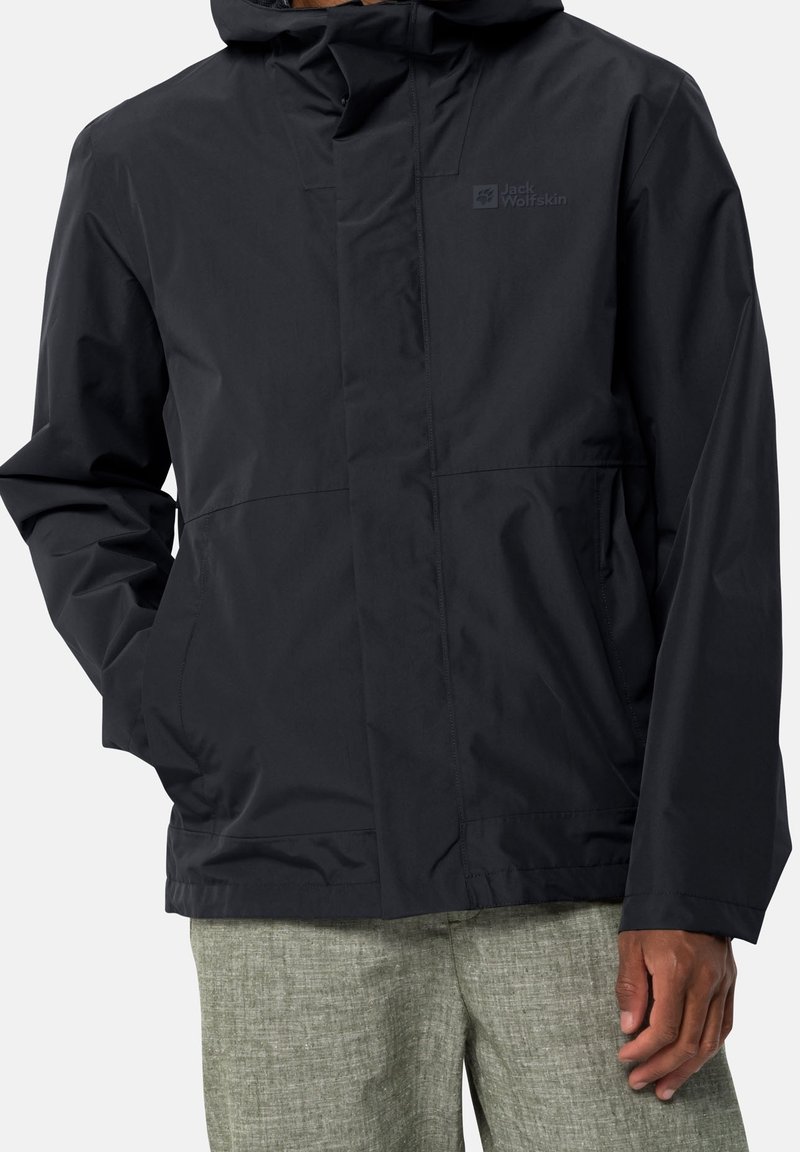 Veste imperméable noire avec capuche, fermeture éclair et deux poches latérales. Tissu léger à texture lisse et branding minimal.