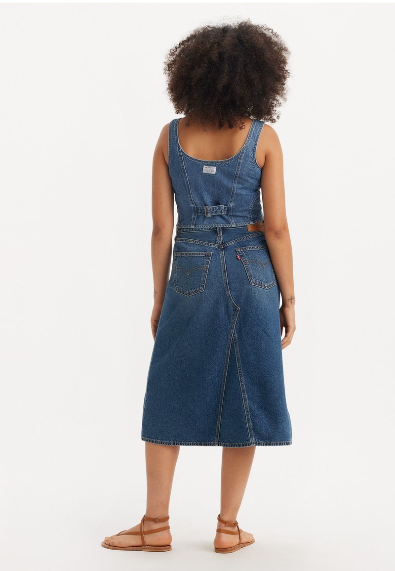 Denim-Midikleid mit verstellbaren Trägern, tailliertem Oberteil und ausgestellt Rock. Verfügt über zwei Gesäßtaschen und ein sichtbares Logo-Tag nahe dem Ausschnitt.