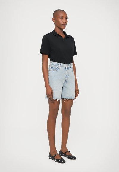 Fekete póló, világoskék farmer rövidnadrág, szakadt szegéllyel, és fekete lapos cipők díszes szegecsekkel. Egyszerű, laza öltözet klasszikus elemekkel.