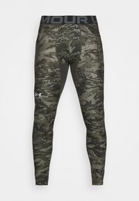 Legginsy sportowe w kamuflażowy wzór w różnych odcieniach zieleni. Posiadają czarną talię z napisem "MOUR" oraz logo Under Armour. Elastyczny materiał.