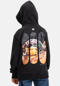 Felpa nera con cappuccio e un grande pannello grafico sulla schiena raffigurante uno skateboarder. Tessuto spesso con tasca a marsupio frontale e cappuccio.