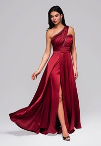 Punainen satiininen iltapuku, jossa on yksikappaleinen olkapäädesign, koristeltu kaula-aukko, korkea halkio ja liehuva helma. Ominaisuuksinaan sileä pinta ja tyylikäs laskeutuvuus.