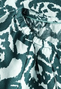 Tessuto a motivo turchese e bianco con scollatura elastica arricciata, caratterizzato da un design floreale o astratto e una trama texturizzata.