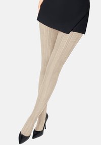 Beżowe rajstopy w wzory z pionowym prążkowaniem, wykonane z elastycznego materiału, połączone z czarnymi butami na wysokim obcasie.