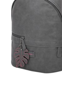 Zaino in finta pelle grigia con forma arrotondata, caratterizzato da una tasca con zip e un dettaglio a forma di foglia rosa come tirazip. Texture liscia.