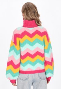 Színes zigzag mintás pulóver magas gallérral, rózsaszín, zöld, sárga és kék árnyalatokkal. Puha, bolyhos anyagból készült.
