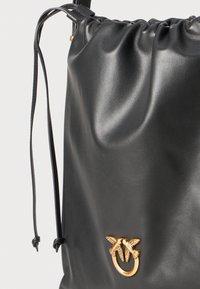 Črn nahrbtnik z vrvico, izdelan iz gladke sintetične usnjene tkanine. Ima zlate okrasne dodatke z dvojnim dizajnom metulja.