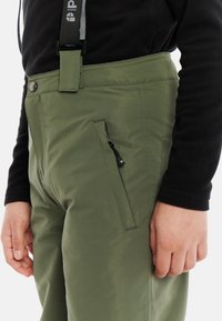 Groene waterdichte broek met verstelbare bretels, een ritszak en een gladde textuur. Voorzien van een knoopsluiting en versterkte stiksels.