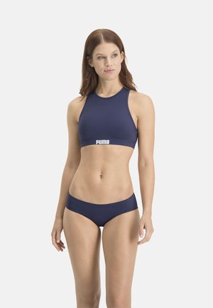 Navy blue sports bra and bikini bottom set made of smooth, stretchy fabric. Features logo on the band and simple, sleek design.