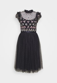 Robe noire avec broderie florale, manches en organza à volants, col montant et jupe en tulle superposée avec des détails à pois. Taille ceinturée.