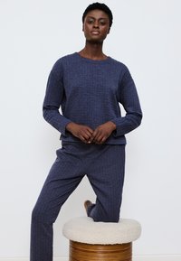 Marineblaues, geripptes Strick-Loungewear-Set mit einem langärmligen Oberteil und passenden Hosen, entspannter Passform und weichem Material.