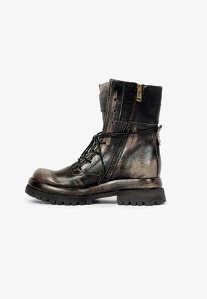 Botte de combat en cuir noir et marron avec fermeture éclair latérale, lacets, semelle robuste et une sangle à boucle à l'arrière, vue du côté droit.