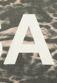 Lettera "A" maiuscola bianca su uno sfondo grigio texture con sottili motivi a onde beige e neri, creando un effetto visivo a strati.