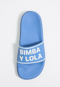 Sinine kummist liug sandaal, millel on lai riba valge tekstiga "BIMBA Y LOLA." Tekstuuriga jalatsisalus ja ümar varvaste kuju.