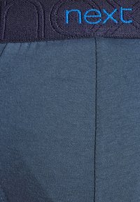 Dunkelblaue Stretchstoff-Boxershorts mit einem marineblauen elastischen Bund, der erhabene Buchstaben aufweist, glatte Textur und enganpassendes Design hat.