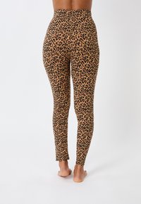 Legginsy w cętkowany wzór w odcieniach brązu i czerni, wysokie w talii, o gładkiej fakturze i dopasowanym kroju. Przycięte do długości kostek. Bez widocznych elementów metalowych.