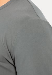 Graues Kurzarmhemd mit glatter Textur und tailliertem Schnitt, mit kontrastierenden Schulterdetails.