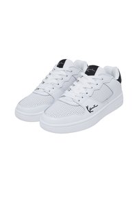 Valged tossud, millel on perforatsiooniga sünteetiline materjal, lamedad paelad ning kontsal must aktsent, mille küljes on musta värvusega allkiri.