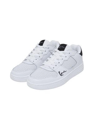 Baltas kedas ar baltas sporta apavs ar perforētu sintētisko materiālu, plakanām šņorēm un melnu akcentu papēžā, sānos ar melnu parakstu.