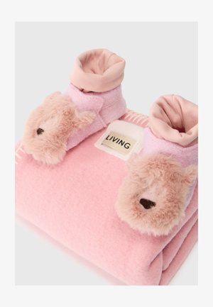 Rožinės fliso šlepetės su meškiuko veidais ir minkštais pūkuotais akcentais. Apykaklės viršus šviesiai rožinės spalvos ir etiketė "LIVING" šviesiame audinio fone.