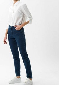 Vit skjorta med subtil textur, parat med mörkblå slim-fit jeans och vita sneakers. Fokus på passform och avslappnad design.