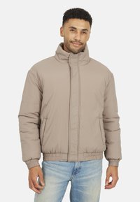 Giubbotto puffer beige chiaro con colletto alto, chiusura zip frontale e polsini elasticizzati. Realizzato in materiale liscio e resistente all'acqua.