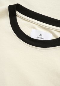 Crème-kleurige sweatshirt met een zwarte geribbelde halslijn. Bevat een label met de tekst "Matinique" dat zichtbaar is in de kraag. Gladde textuur.