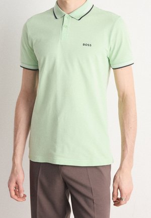 Hellgrünes Poloshirt mit flachem Kragen, kontrastierenden schwarzen Akzenten und gesticktem "BOSS"-Logo auf der linken Brust. Aus Baumwolle, mit kurzen Ärmeln.