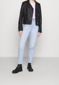 Mustat nahkainen biker-takki hopeisilla vetoketjuilla, vaaleanlila sitruunapaita, vaaleansiniset korkea vyötäröiset farkut ja mustat nauhakiinnitteiset maiharit.