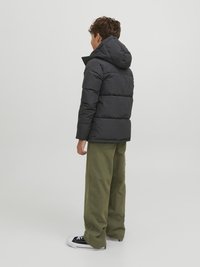 Black puffer jacket with a hood, featuring a quilted design and a relaxed fit, paired with loose olive green pants and black sneakers.